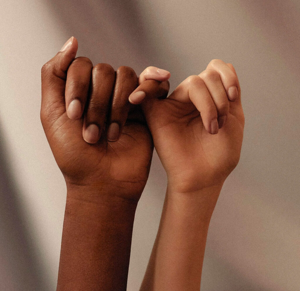 Dos manos de diferentes tonos de piel entrelazadas, formando un símbolo de unión y solidaridad.